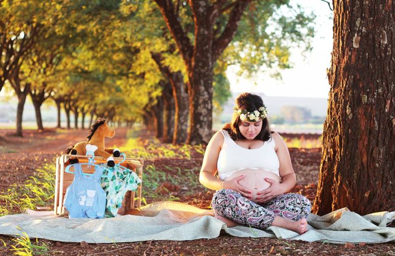 schwangere Frau sitzend auf einer Wiese