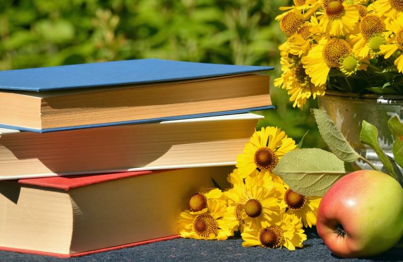 Blumen und Bücherstapel und ein Apfel